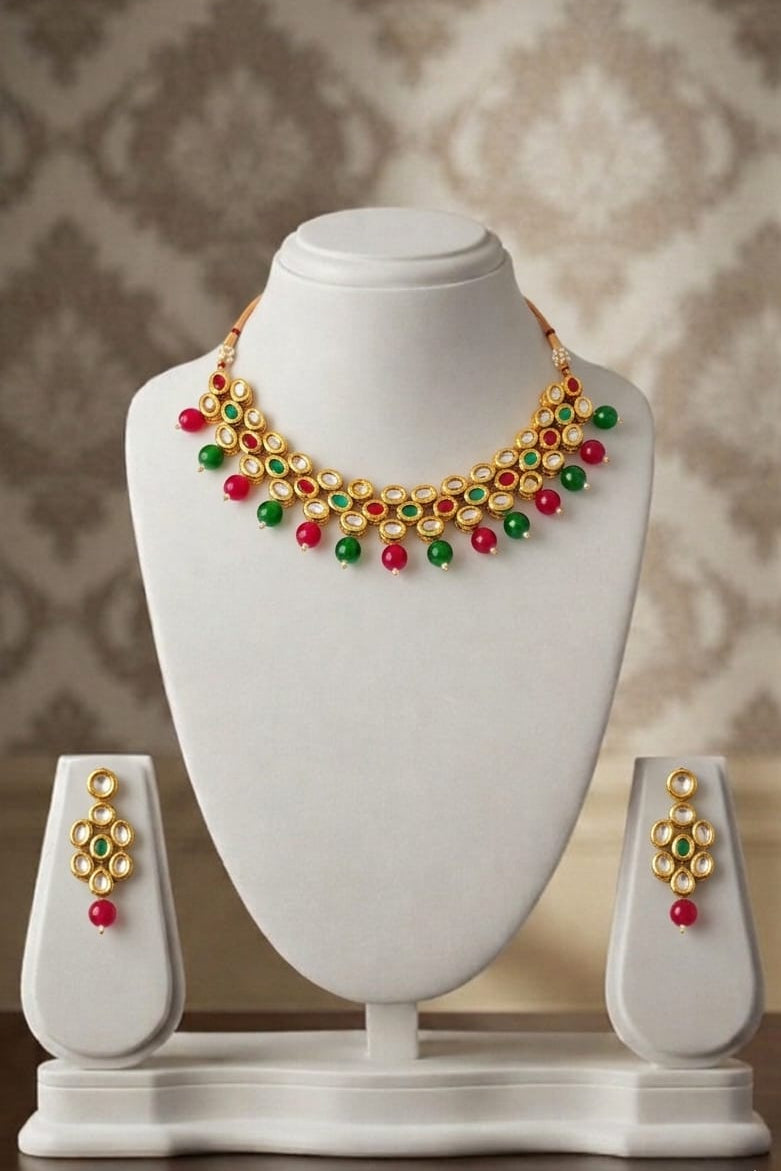Stunning gold-toned kundan necklace & earring set with vibrant red & green bead drops