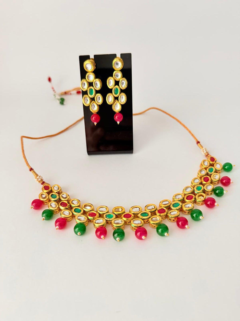 Stunning gold-toned kundan necklace & earring set with vibrant red & green bead drops