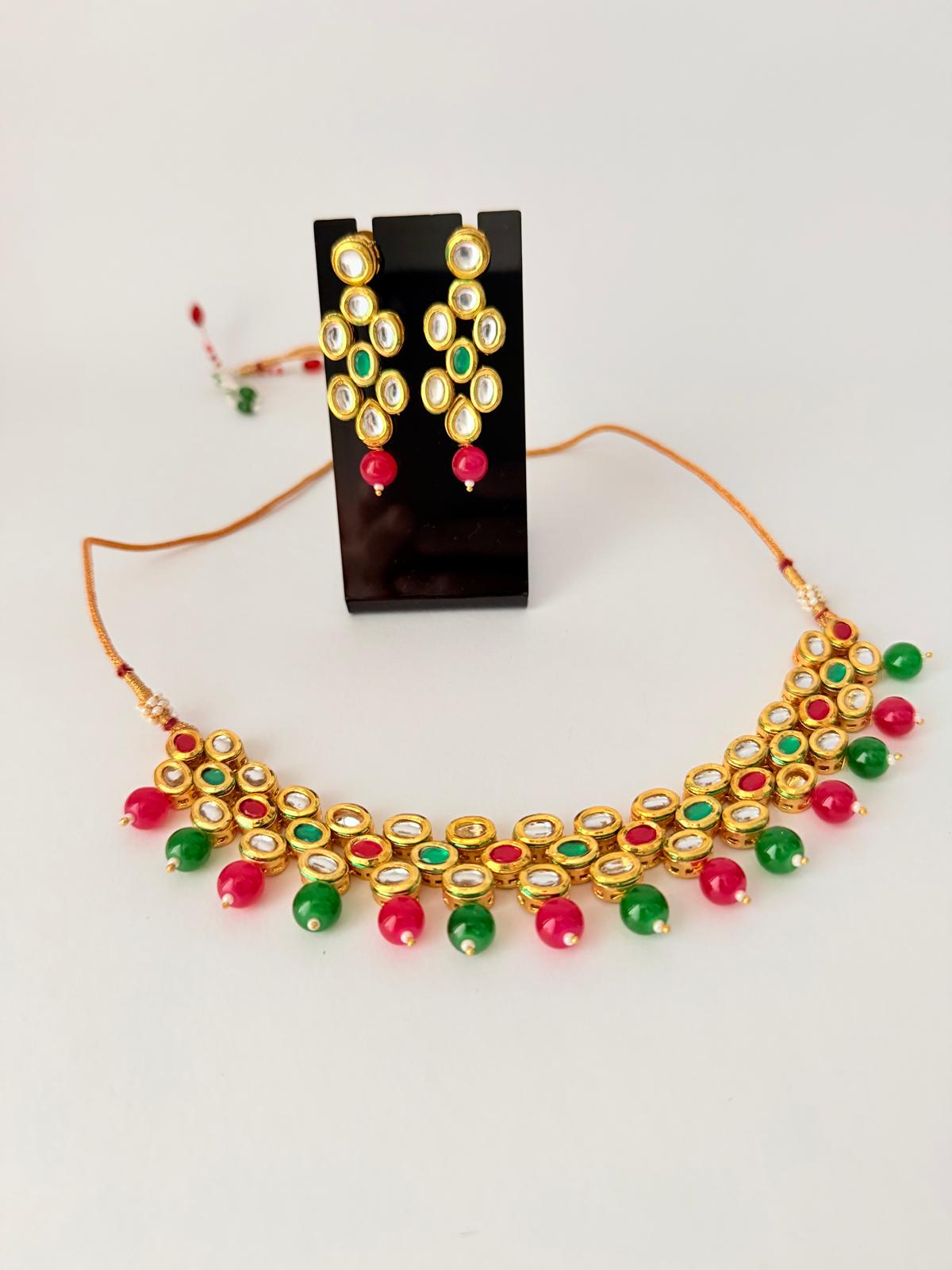 Stunning gold-toned kundan necklace & earring set with vibrant red & green bead drops