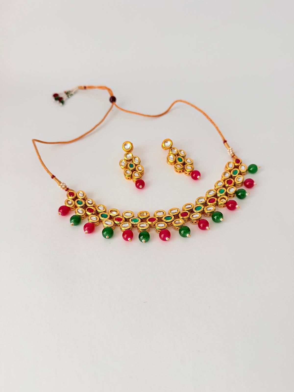 Stunning gold-toned kundan necklace & earring set with vibrant red & green bead drops