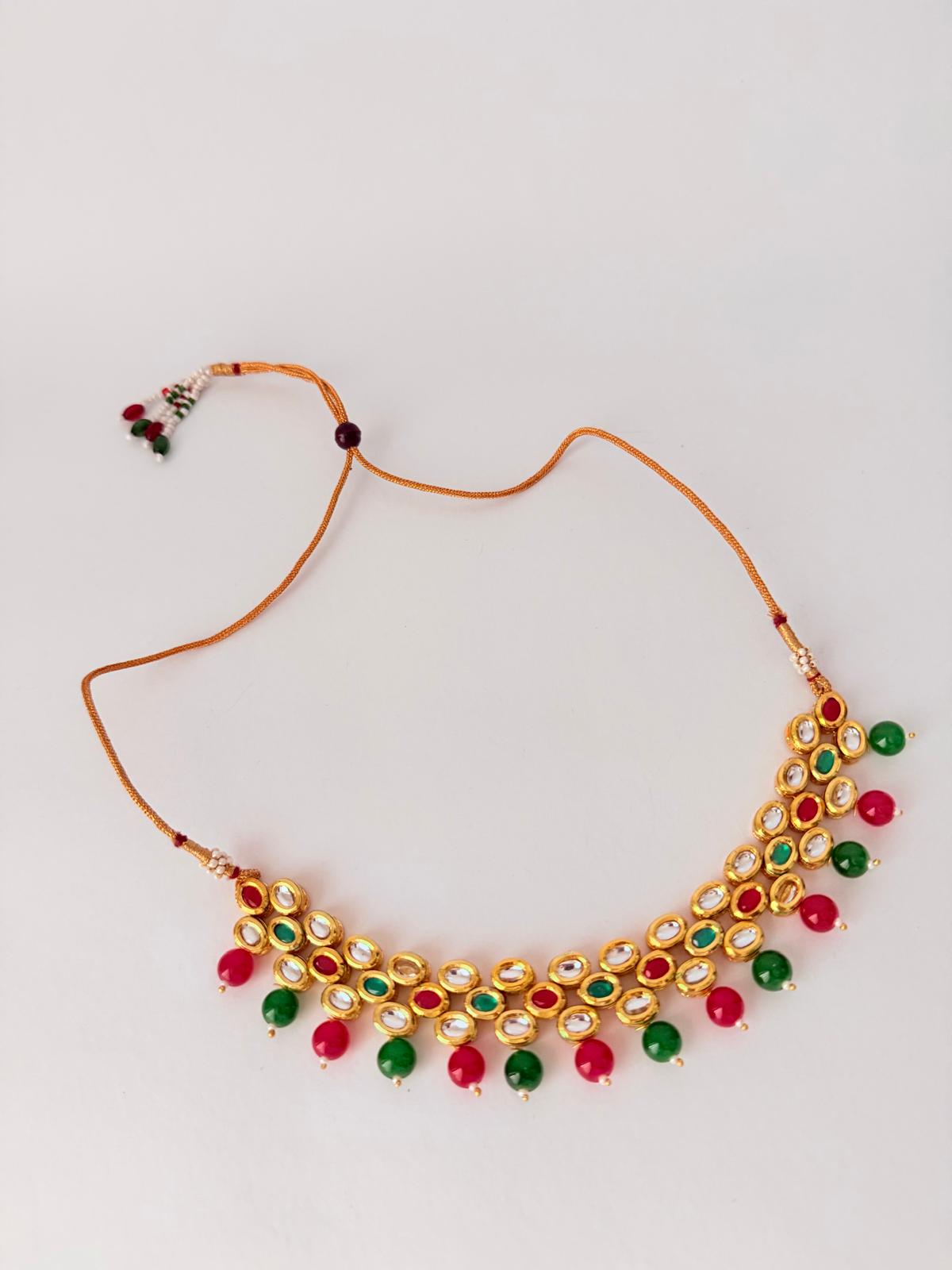 Stunning gold-toned kundan necklace & earring set with vibrant red & green bead drops